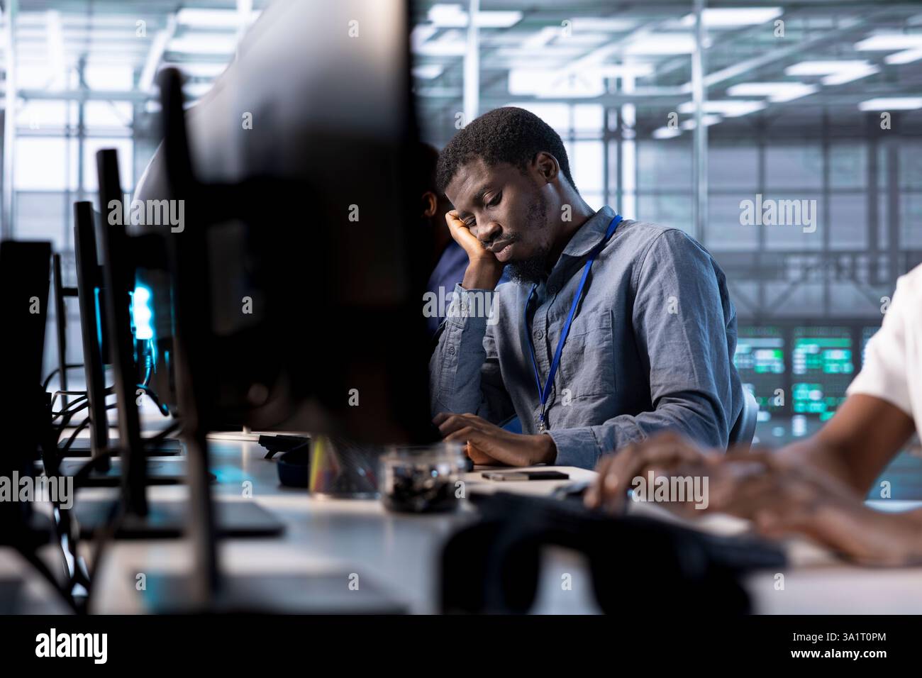 Bored data center engineer mindlessly using programming languages to construct algorithms and build applications. Fatigued server room employee tired of debugging and optimizing code Stock Photo