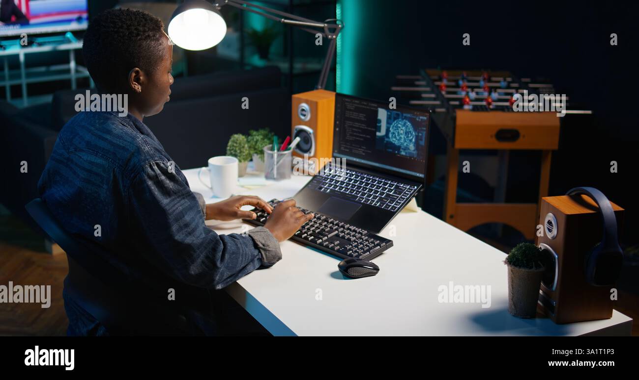 AI expert writes code on laptop in apartment office using Java programming languages. Artificial intelligence programmer remotely working on fixing database errors while working from home, camera B Stock Photo