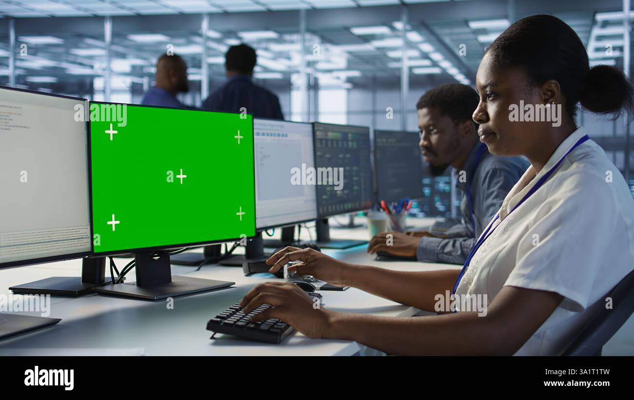 Software developer in server farm ensuring data remains shielded from potential threats using mockup PC. IT expert safeguarding data center against hackers with green screen computer, camera A Stock Photo