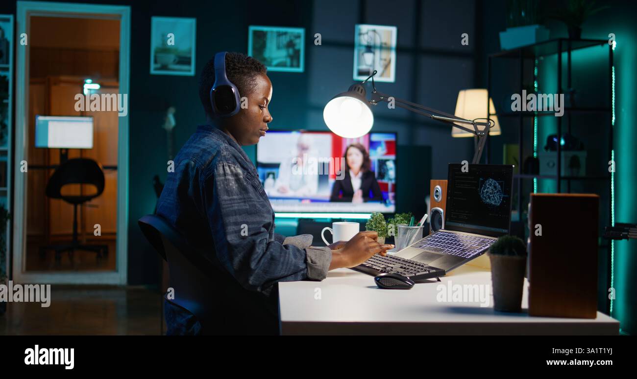 Computer scientist updating artificial intelligence neural networks, writing binary code scripts. Remote worker in apartment office uses digital device programming to upgrade AI, camera B Stock Photo