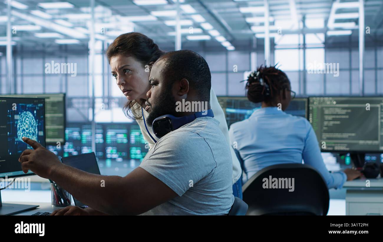 Teamworking colleagues updating AI systems, writing intricate binary code scripts on PC and laptop. Team of engineers using programming to upgrade artificial intelligence simulation model, camera A Stock Photo