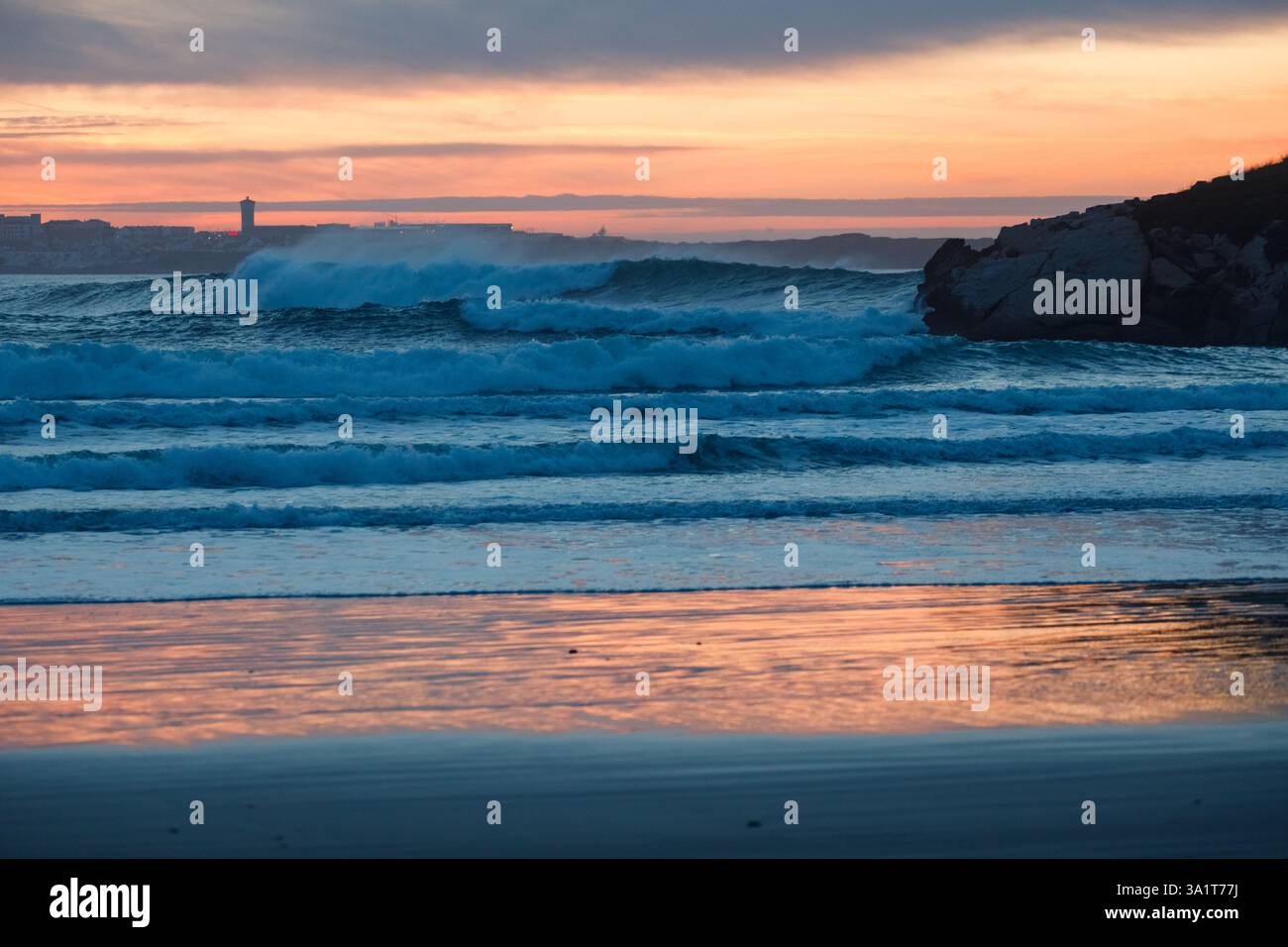 Waves breaking on the rocky coastline at sunset in Peniche Stock Photo