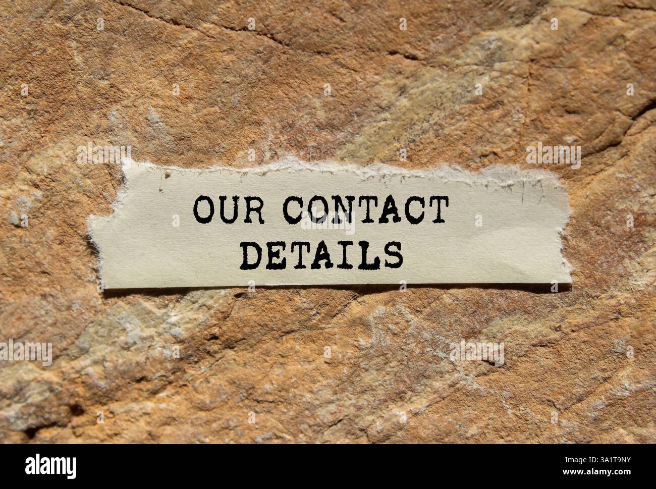 Our contact details message written on ripped torn paper on stone ...