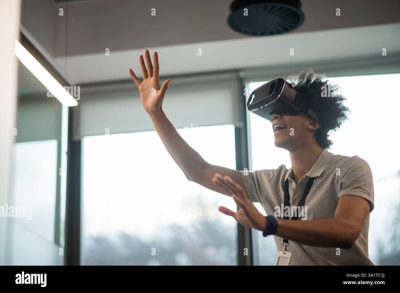 Man with Afro hairstyle using vr headset interacting with virtual environment Stock Photo