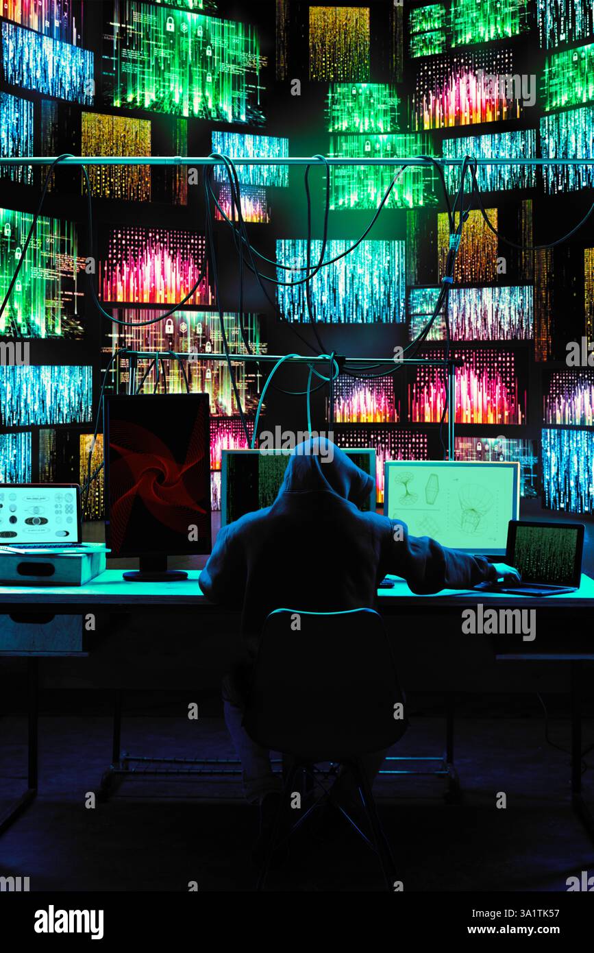Hacker working on multiple devices while encrypted data flows across digital walls. Stock Photo