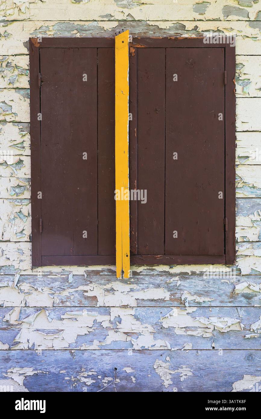 A weathered wooden window shutter on a peeling paint wooden wall Stock ...