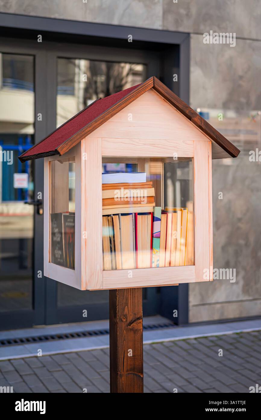 Wooden street library box filled with colorful books standing in front ...
