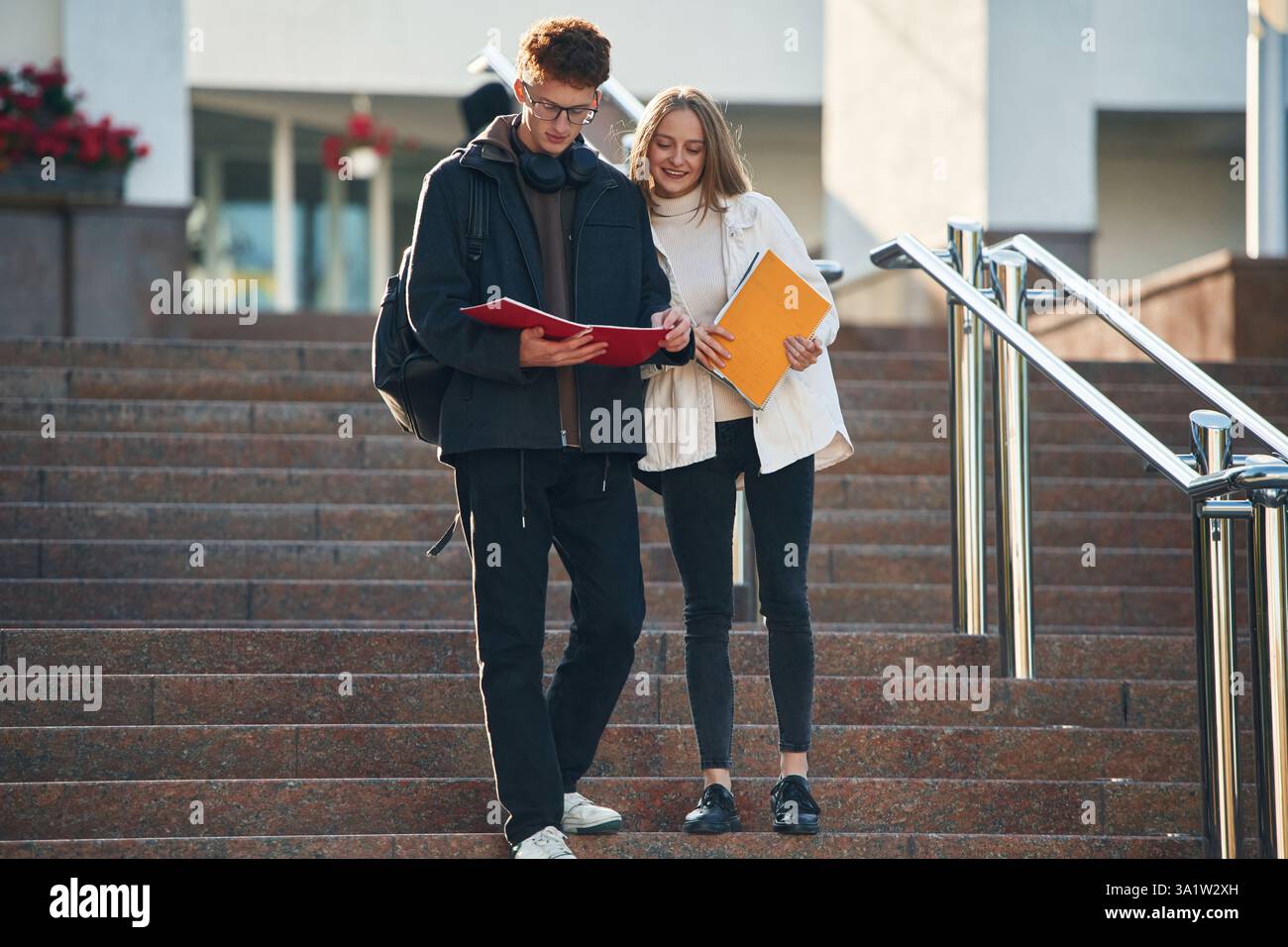 Front view, walking the stairs. Two young students are together outdoors. Stock Photo