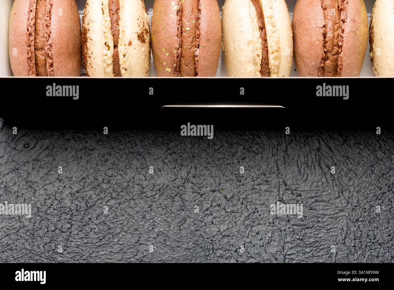 Macaroons in a black cardboard box on a dark background. Stock Photo