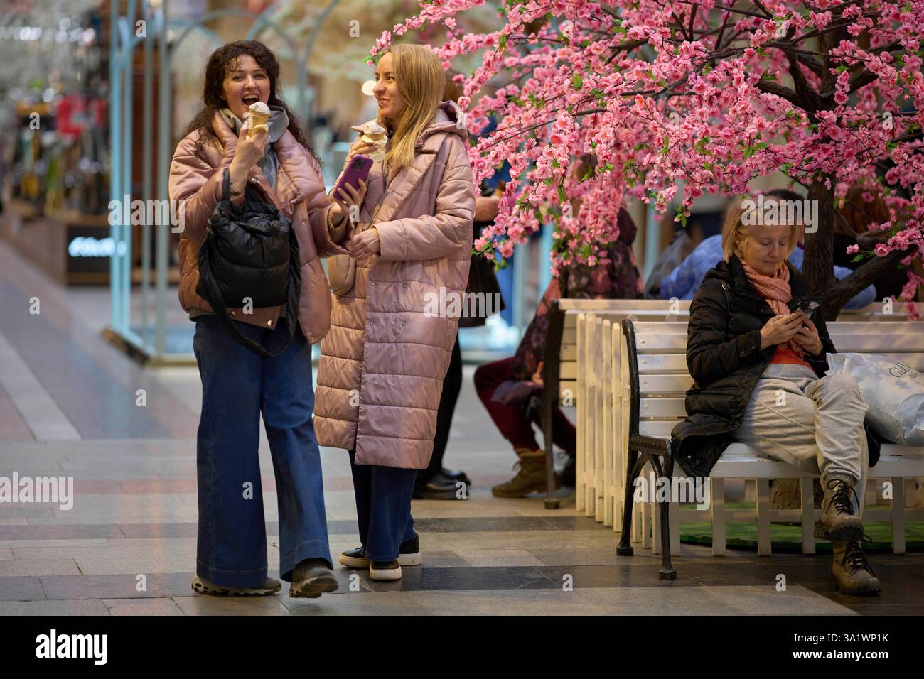 Women eat ice-cream inside the GUM department store, decorated for