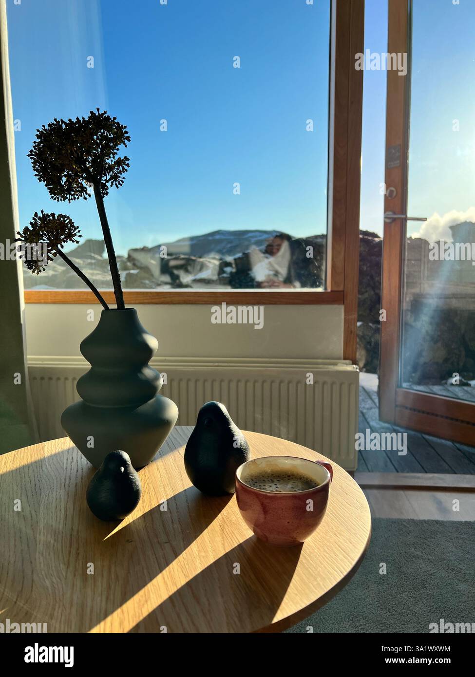 Cozy interior with coffee, decor, and mountain view through window. - Smartphone Captured Stock Image