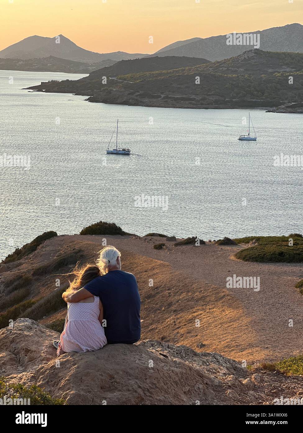 Grandfather and granddaughter embracing while watching the sunset - Smartphone Captured Stock Image