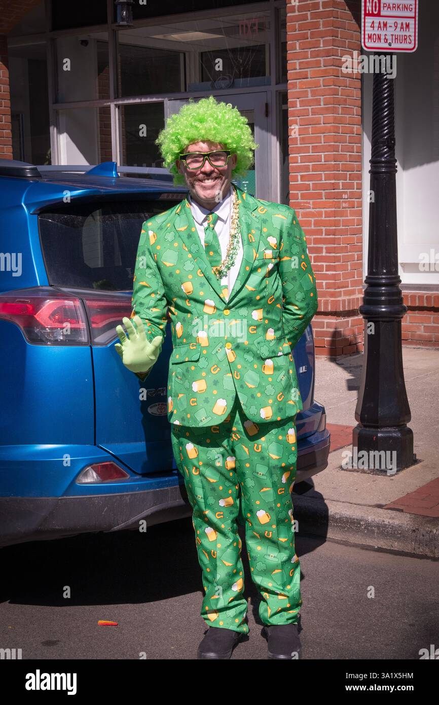A man in a green suit with beer glasses, horseshoes, green tie & a green wig at the St. Patrick's Day Parade in Beacon, New York. Stock Photo