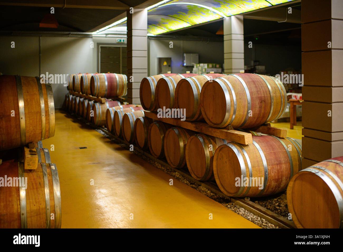A long row of wine barrels stretches through the winery’s underground ...