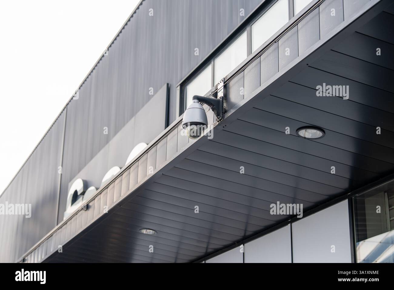 Security camera mounted on modern building facade capturing urban life ...