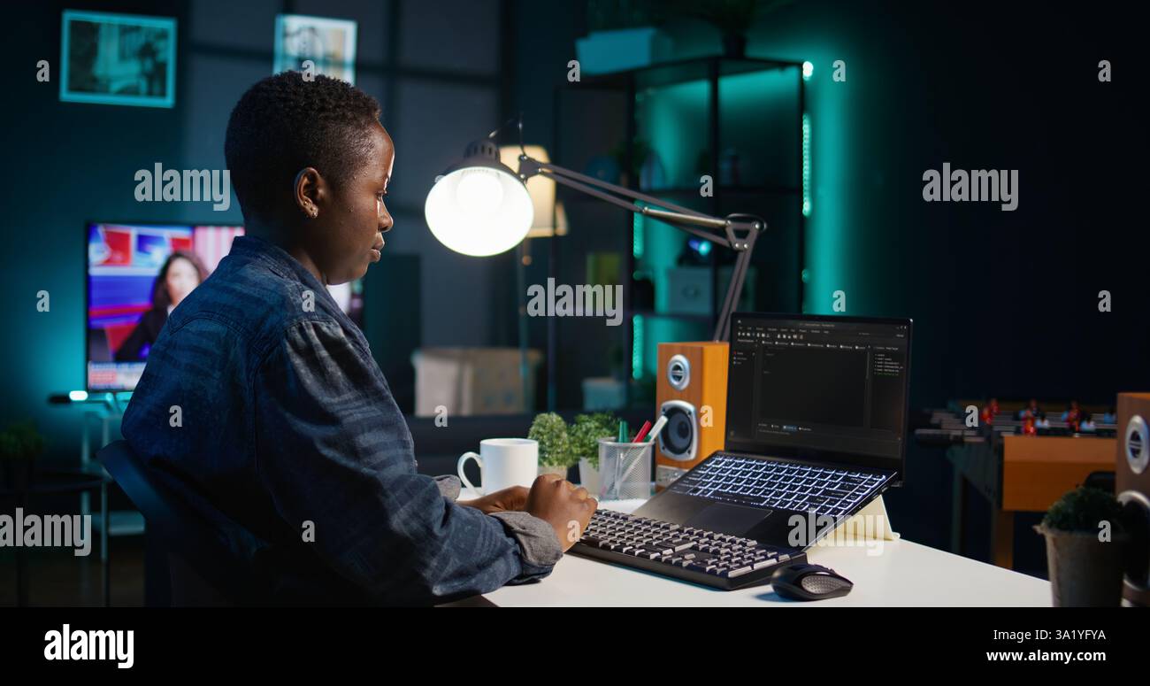 Software developer writes code on laptop screen while in apartment office using Java programming languages. Programmer remotely working on fixing database errors while working from home, camera B Stock Photo