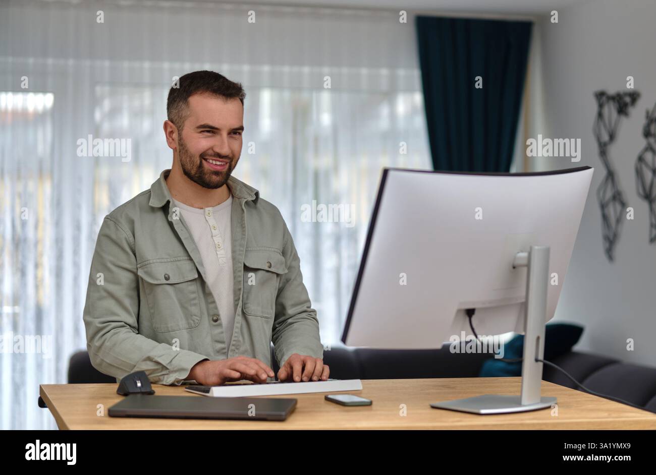 A happy man using a desktop computer while working at a home. Stock Photo