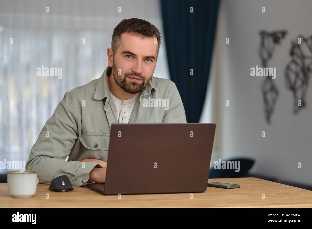 A happy man using a laptop while working at home office. Stock Photo