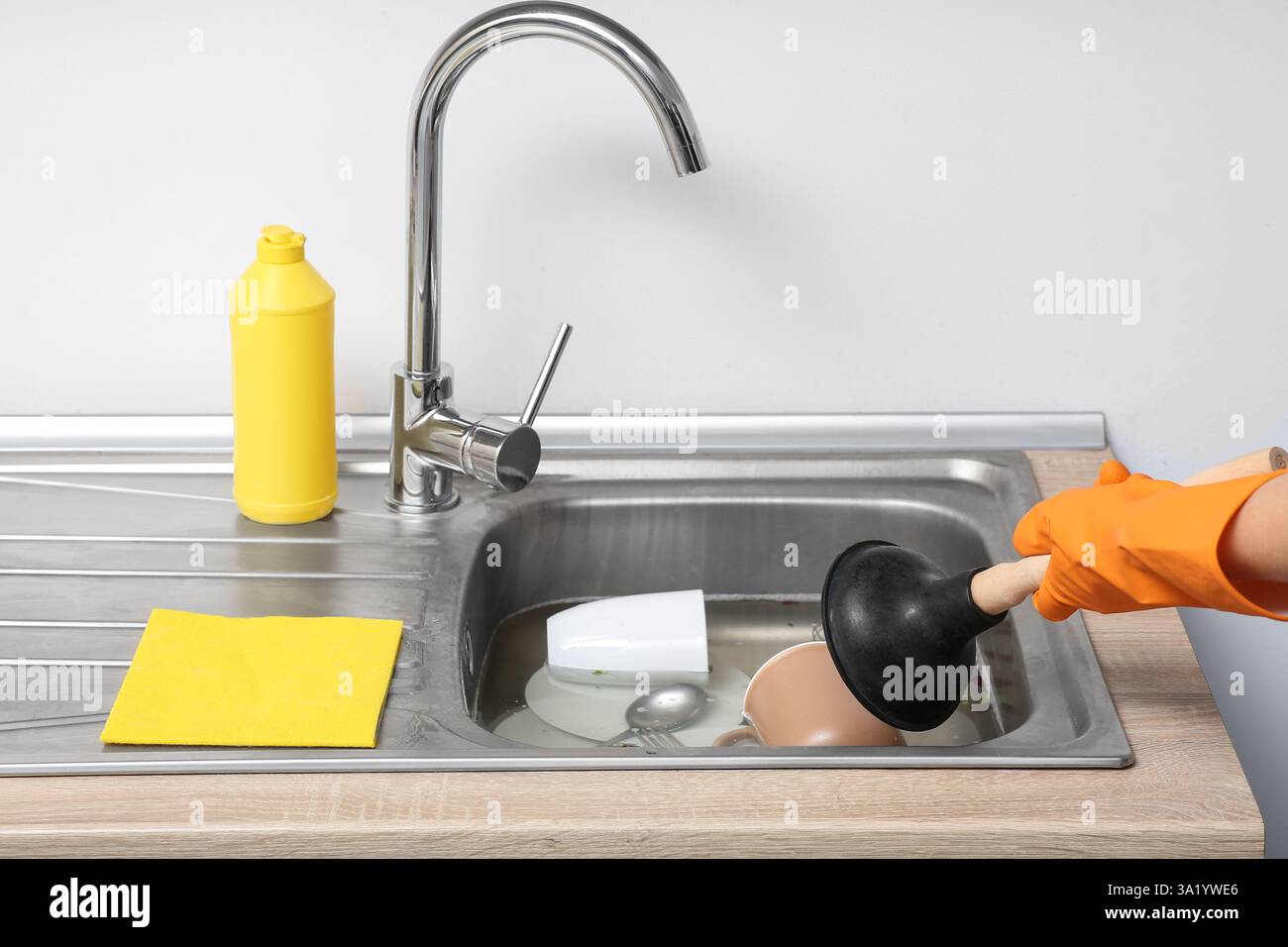 Woman cleaning clogged kitchen sink with plunger Stock Photo - Alamy
