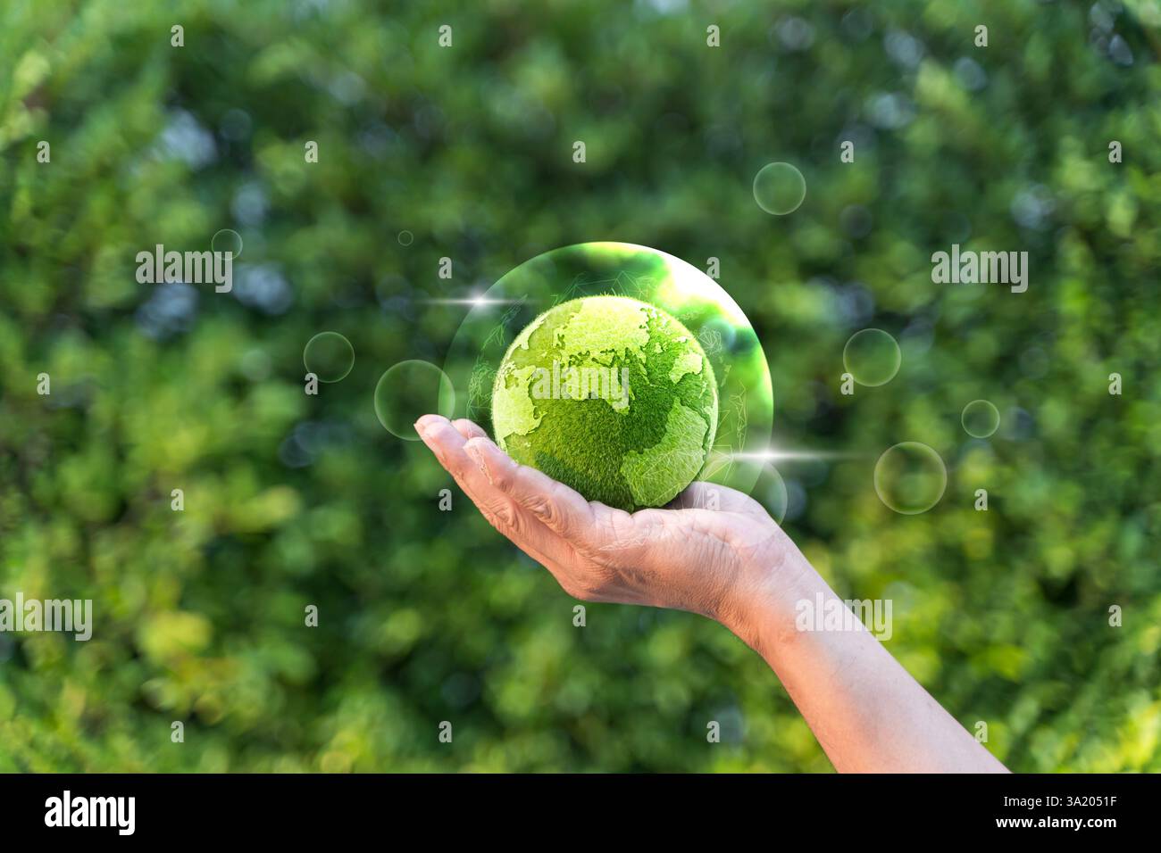 Hand holding a green grass earth globe in bubble with light reflection ...