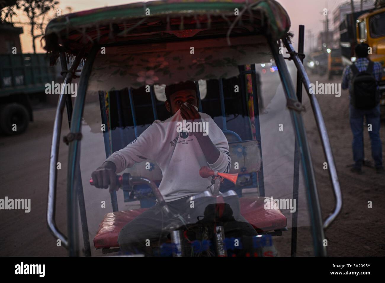 FILE - An auto rickshaw driver covers his face to protect himself from
