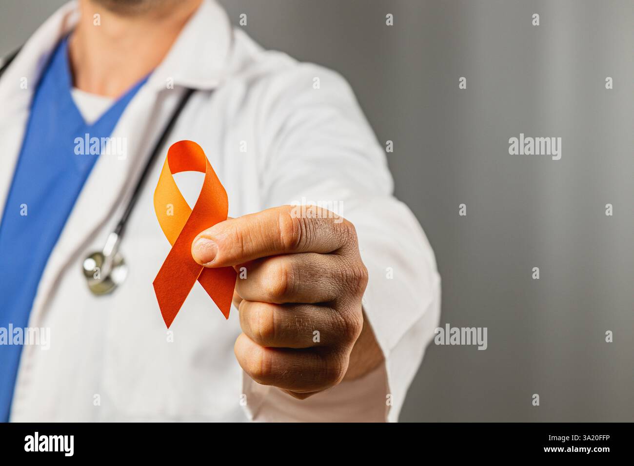 A healthcare professional in a white coat and blue scrubs holds an ...
