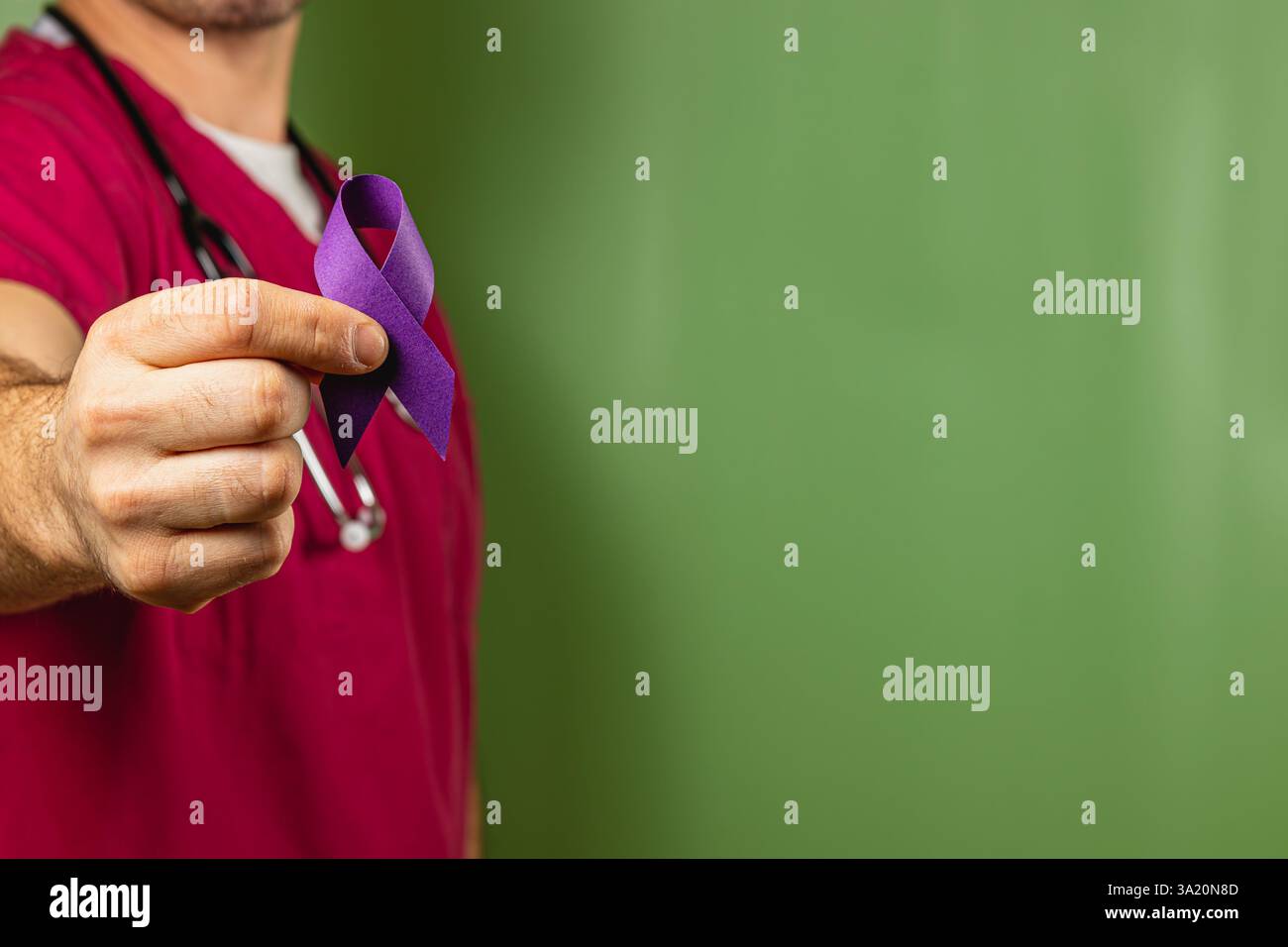 A healthcare professional holds a purple ribbon in front of a green ...