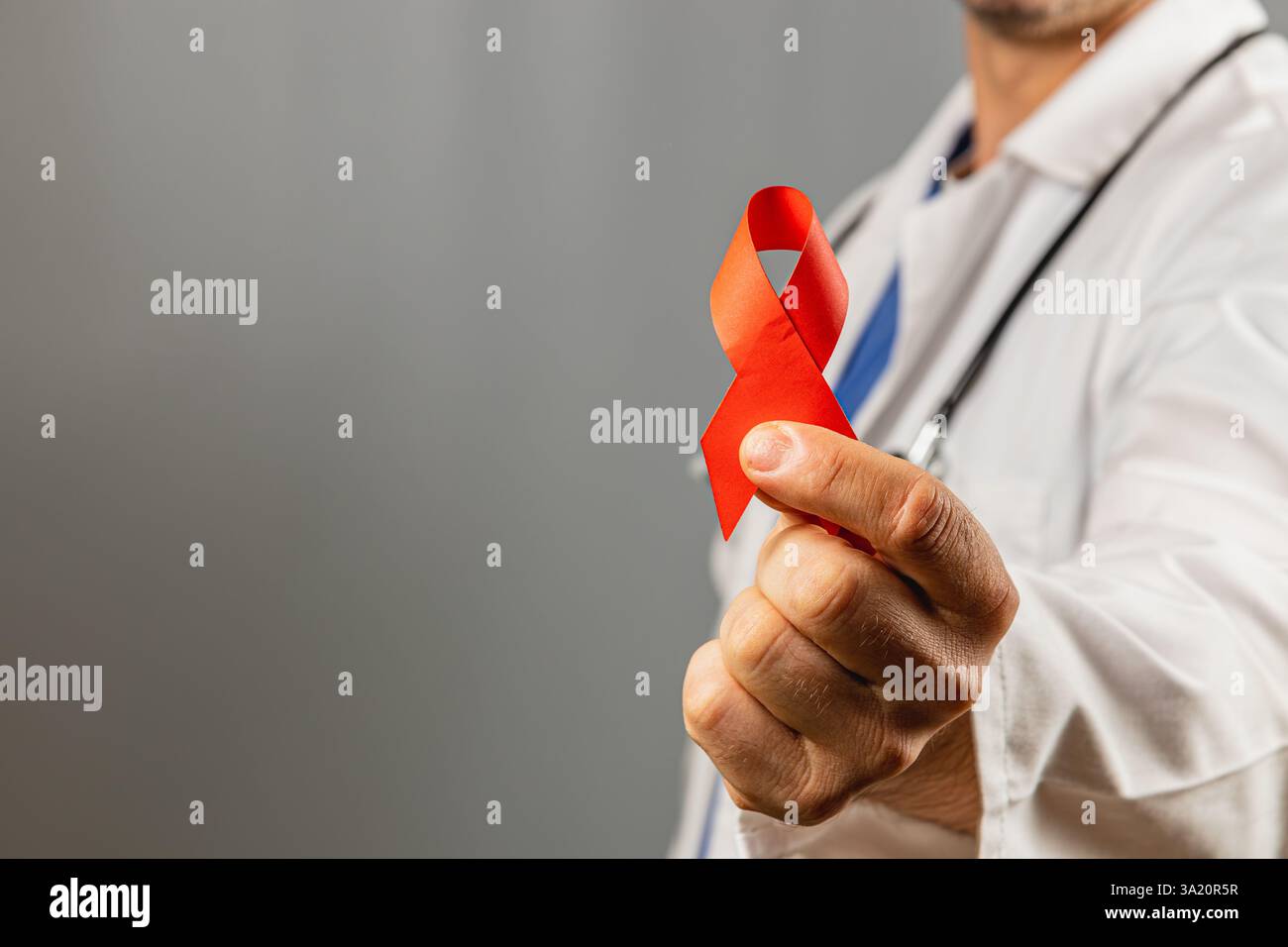 A healthcare professional displays a red ribbon emphasizing the ...