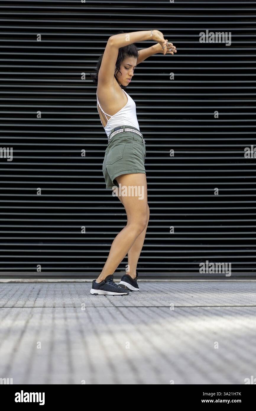 Confident young woman dancing against a modern backdrop in the street Stock Photo