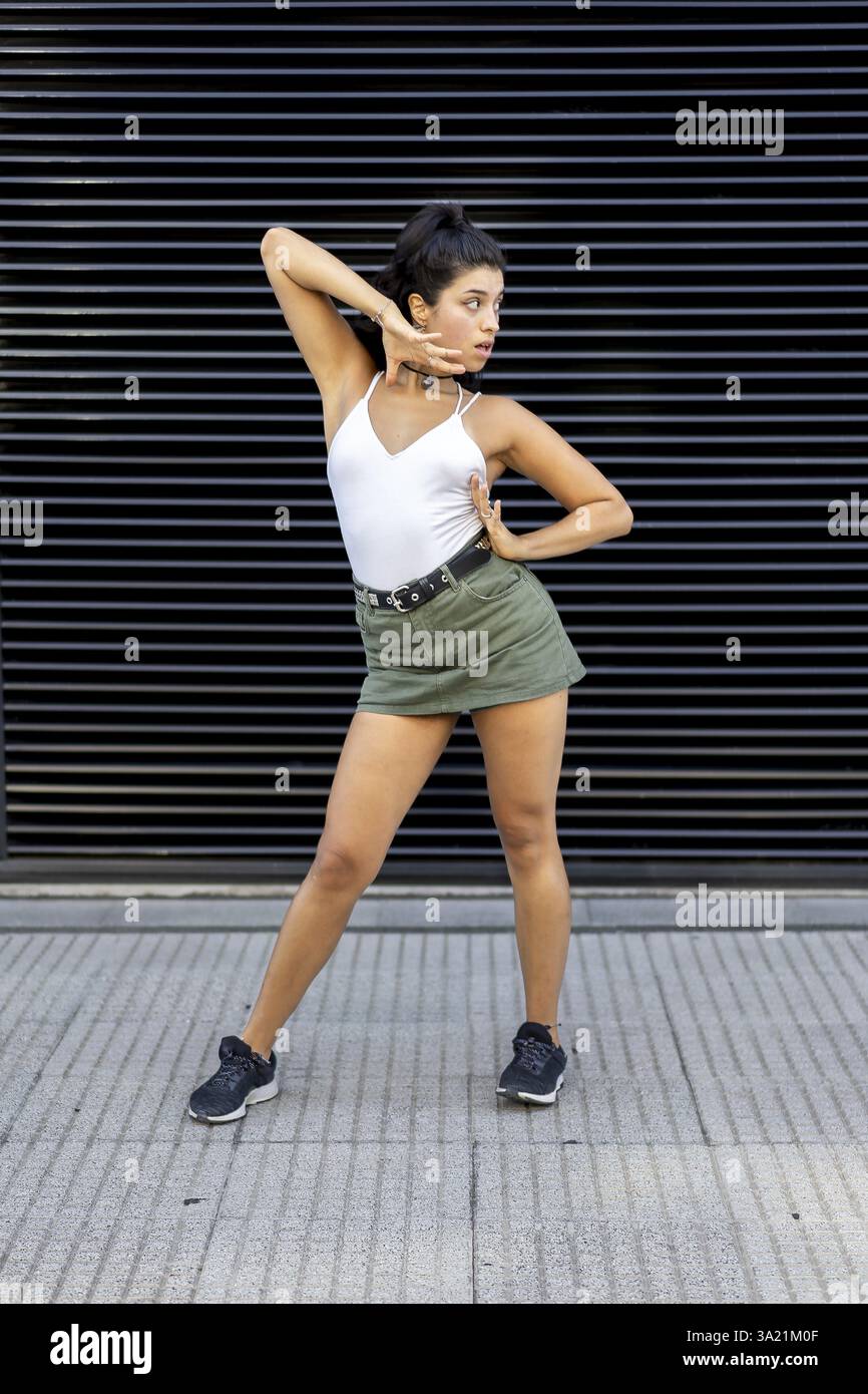 Confident young woman dancing against a modern backdrop Stock Photo
