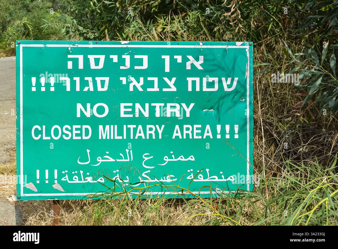 Warning sign indicating restricted military area written in Hebrew, English and Arabic languages. Military area, keep out, no entry warning sign on mi Stock Photo