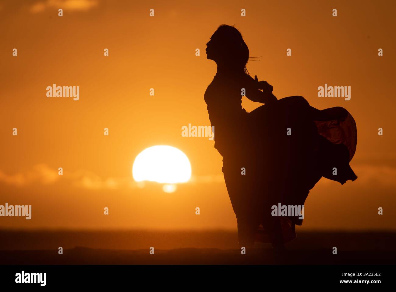 silhouette of a woman in flowing dress in the sunset Stock Photo - Alamy