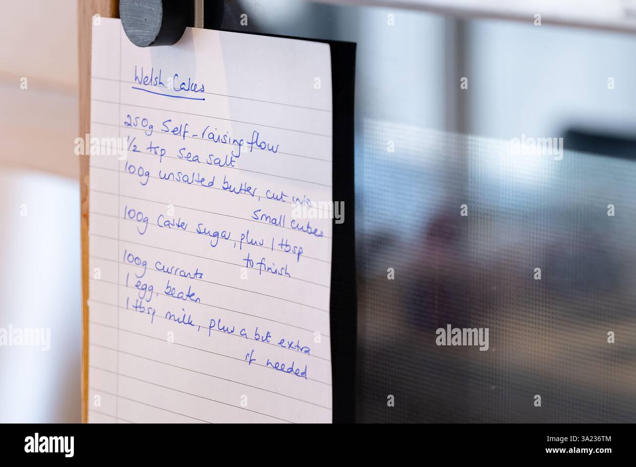 UK. A handwritten note showing the ingredients to make Welsh Cakes attached to an oven by the baker. The note paper is held in place by a magnet Stock Photo