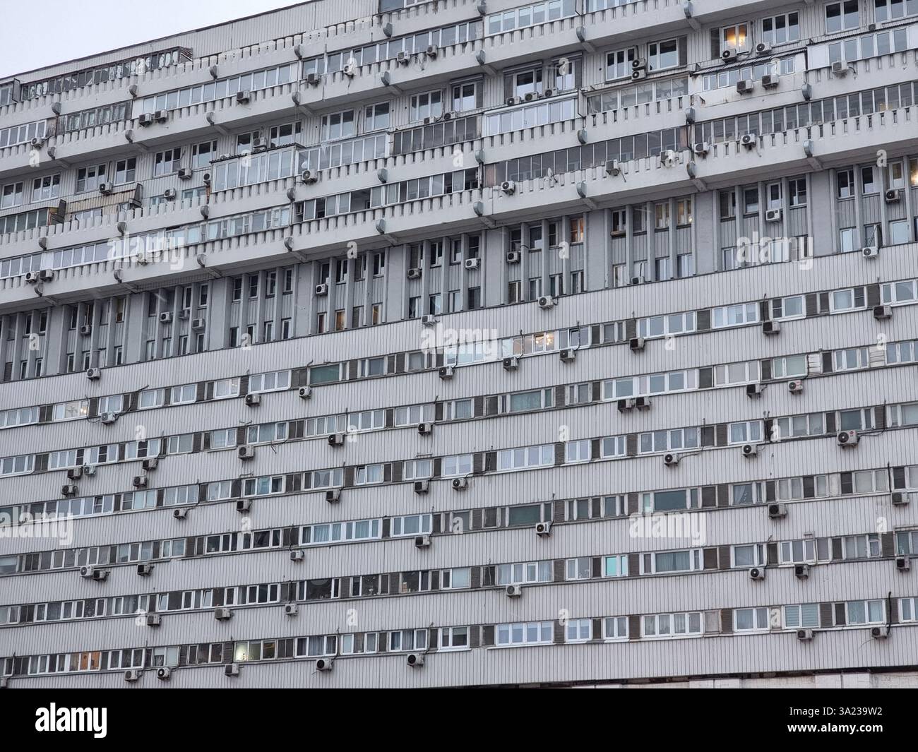 Facade of residential building with many external air conditioners and windows, forming a rectangular pattern - Smartphone Captured Stock Image