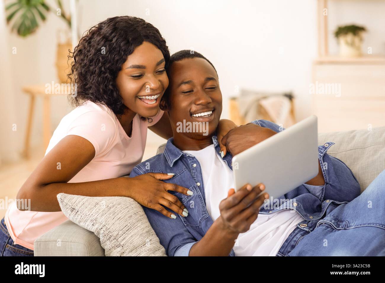 Cheerful black couple using digital tablet at home Stock Photo