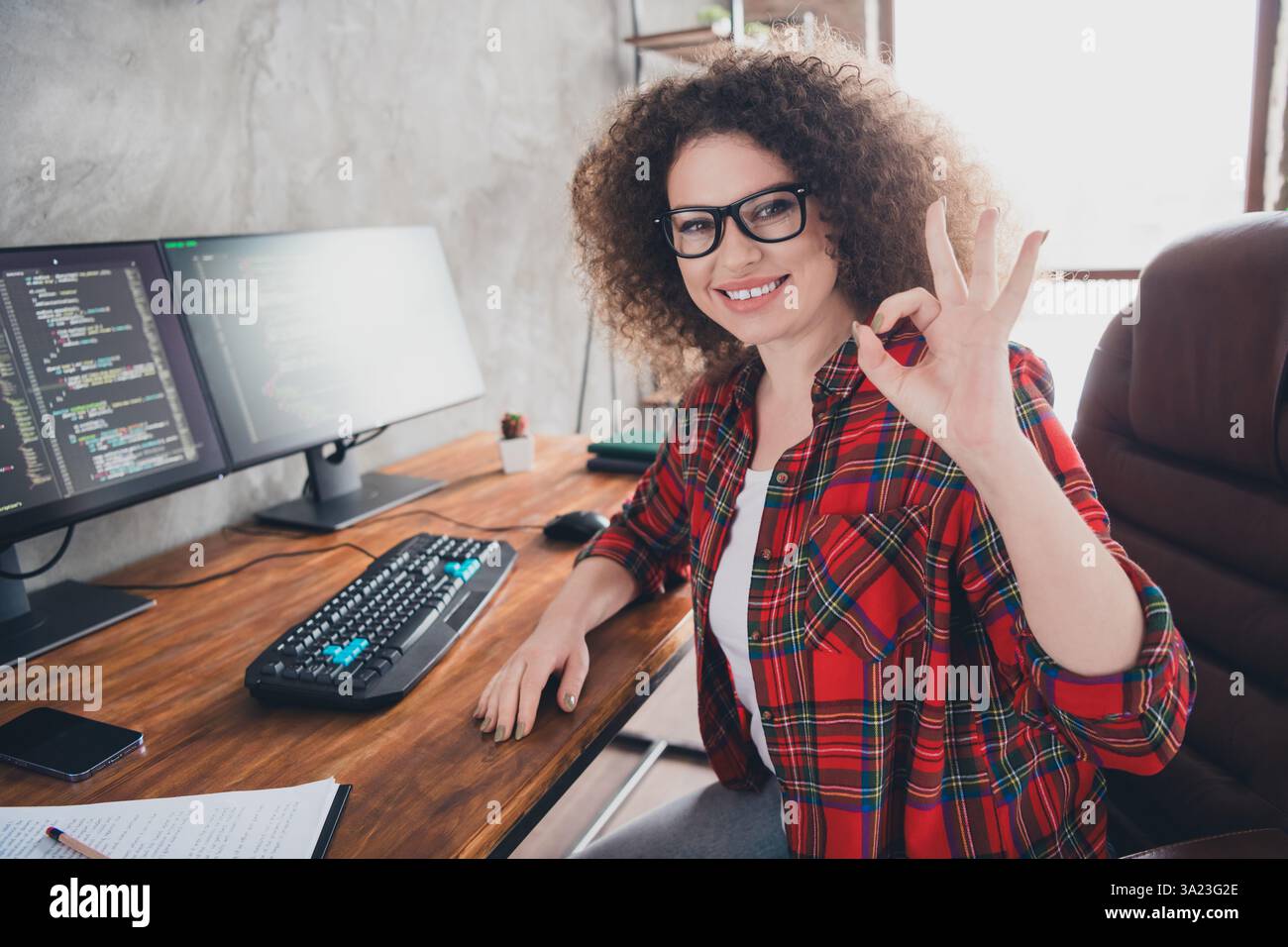 Smiling Female Programmer Gestures in a Comfortable Home Office with Dual Monitors Coding Workspace Stock Photo