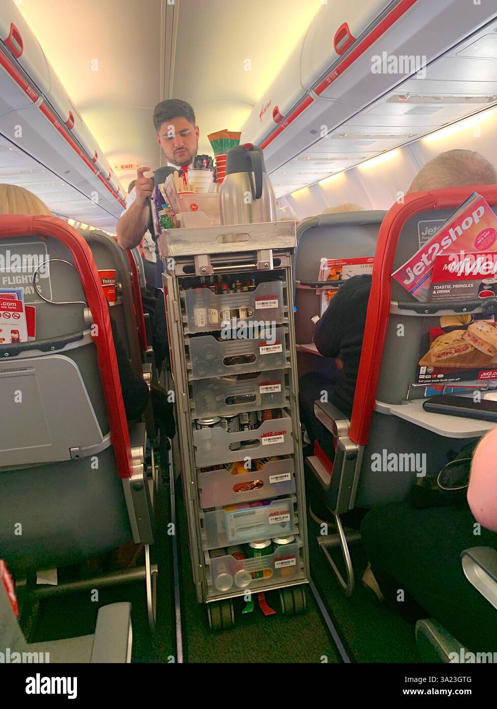 Jet 2 in flight trolley airliner passengers passenger staff working sell selling goods tea beer drink food Birmingham Police Policeman waiting sit sat - Smartphone Captured Stock Image