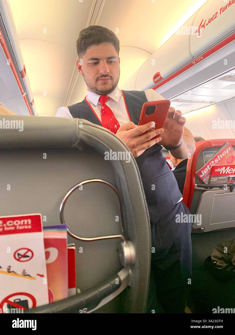 Jet 2 in flight trolley airliner passengers passenger staff working sell selling goods tea beer drink food Birmingham Police Policeman waiting sit sat - Smartphone Captured Stock Image