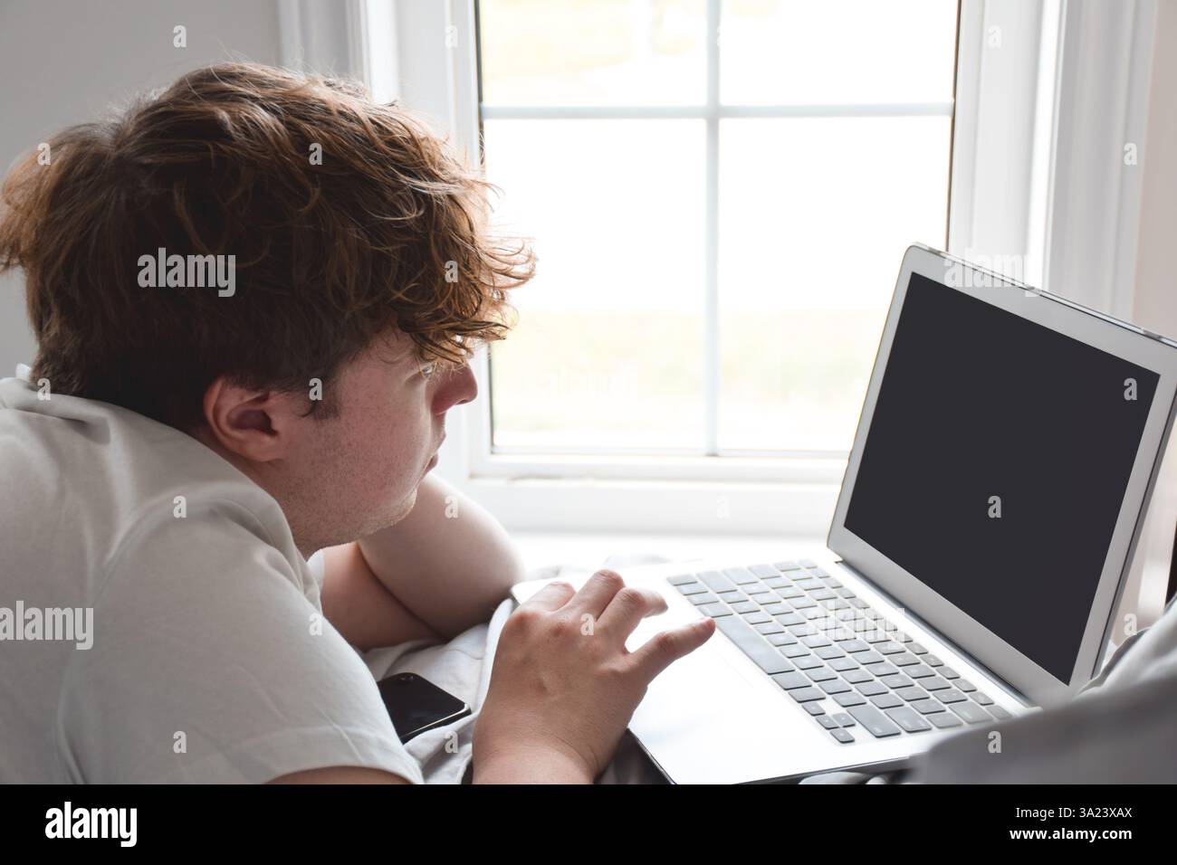 Young man laying on bed using laptop computer Stock Photo