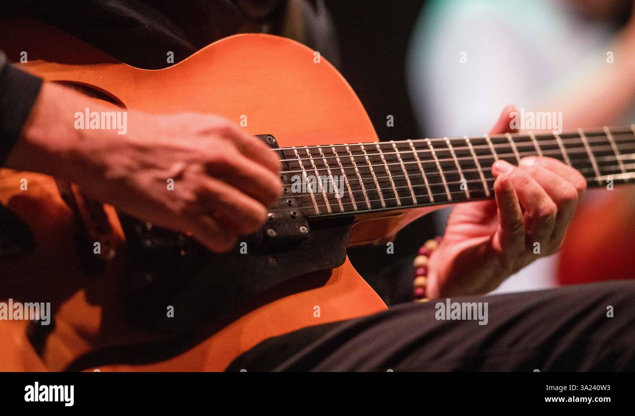 A musician skillfully plays the guitar during an evening jazz concert creating a vibrant atmosphere filled with music. Stock Photo
