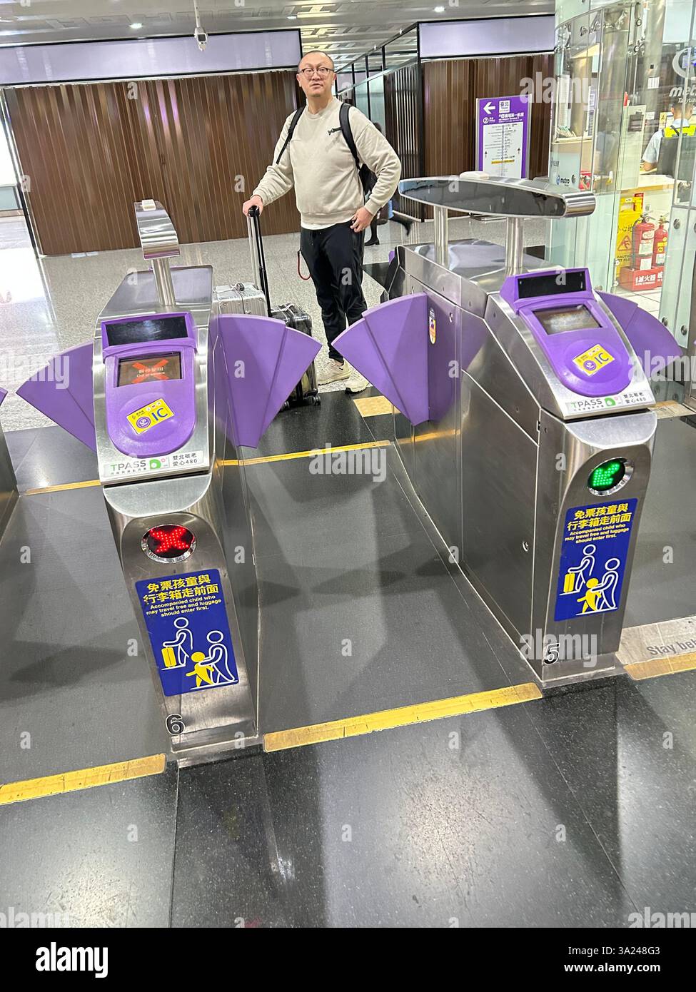 Taipei, Taiwan, Man with Suitcase entering Metro Turnstiles, View inside Metro, tube train Subway entrance, - Smartphone Captured Stock Image