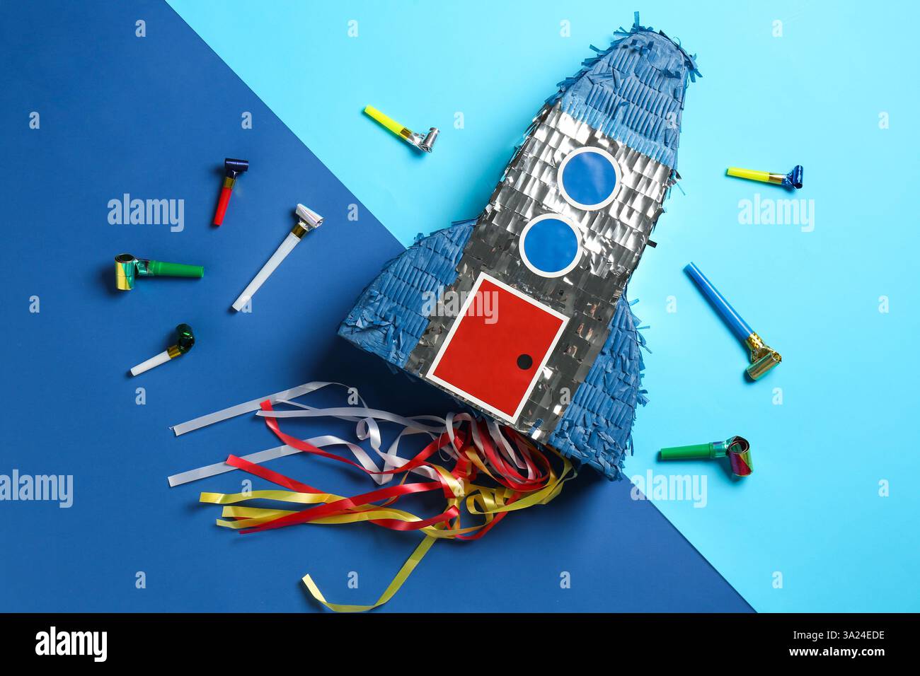 Bright pinata in shape of spaceship and blowers on blue background ...