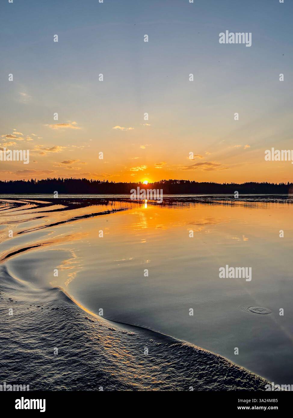 A golden sunset reflects on the calm lake surface, with gentle ripples shaping the water. The sky transitions from orange to blue, creating a peaceful - Smartphone Captured Stock Image A golden sunset reflects on the calm lake surface, with gentle ripples shaping the water. The sky transitions from orange to blue, creating a peaceful - Smartphone Captured Stock Image