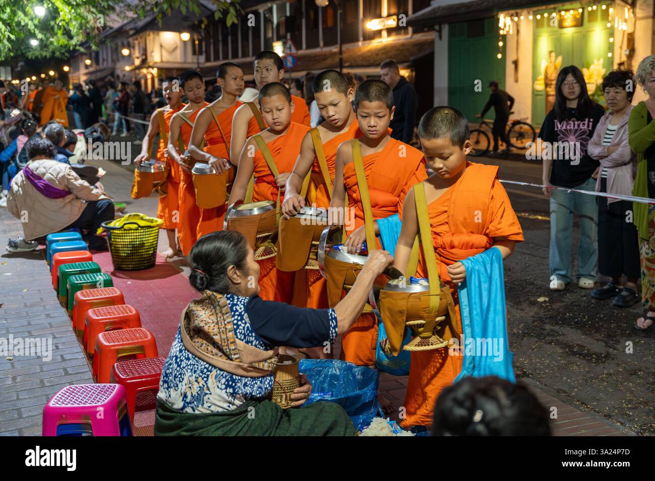 Morning alms giving in Luang Prabang, Tak Bat, Buddhist ritual. At dawn, barefoot monks dressed in saffron robes silently stroll through the streets Stock Photo