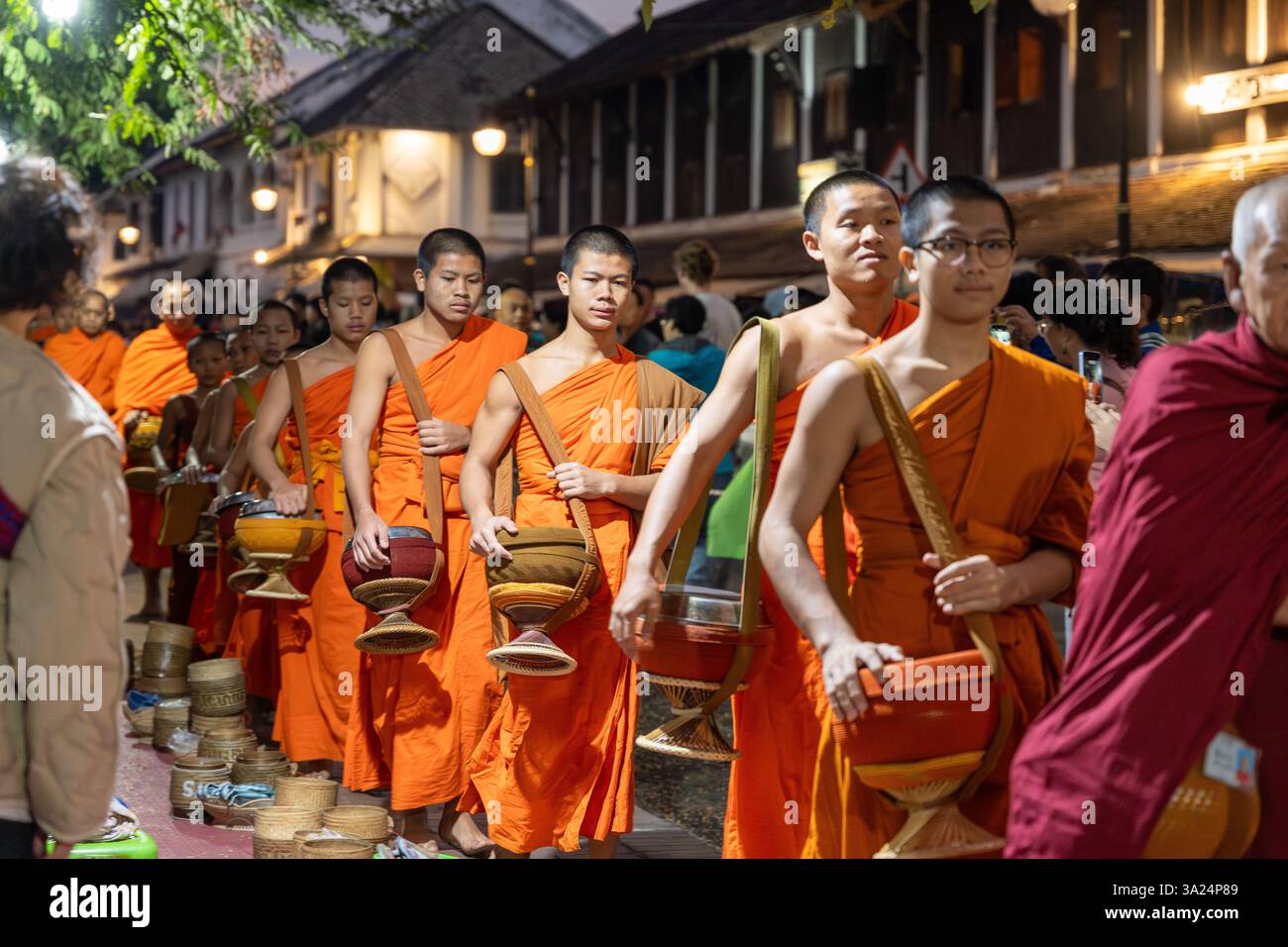 Morning alms giving in Luang Prabang, Tak Bat, Buddhist ritual. At dawn, barefoot monks dressed in saffron robes silently stroll through the streets Stock Photo