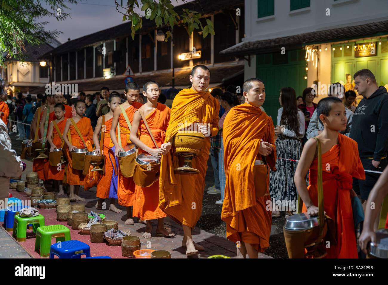 Morning alms giving in Luang Prabang, Tak Bat, Buddhist ritual. At dawn, barefoot monks dressed in saffron robes silently stroll through the streets Stock Photo