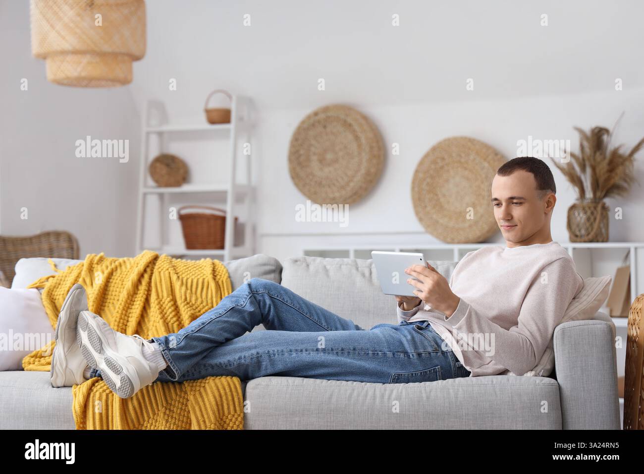 Young man using tablet computer on sofa at home Stock Photo