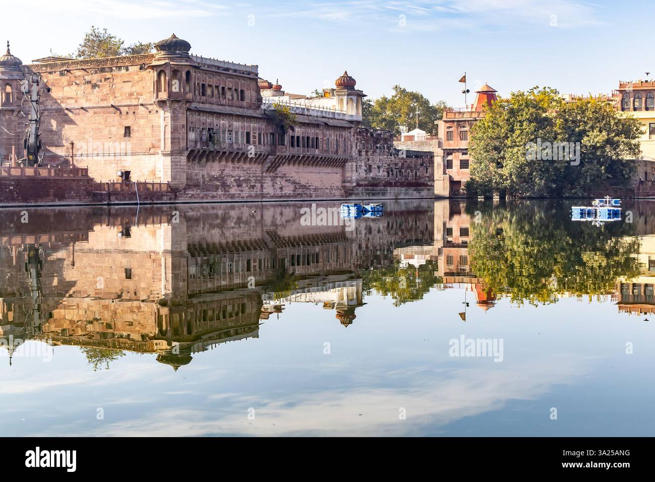 pristine calm lake with water reflection of houses around at morning image is taken at Gulab sagar talab jodhpur rajasthan india. Stock Photo