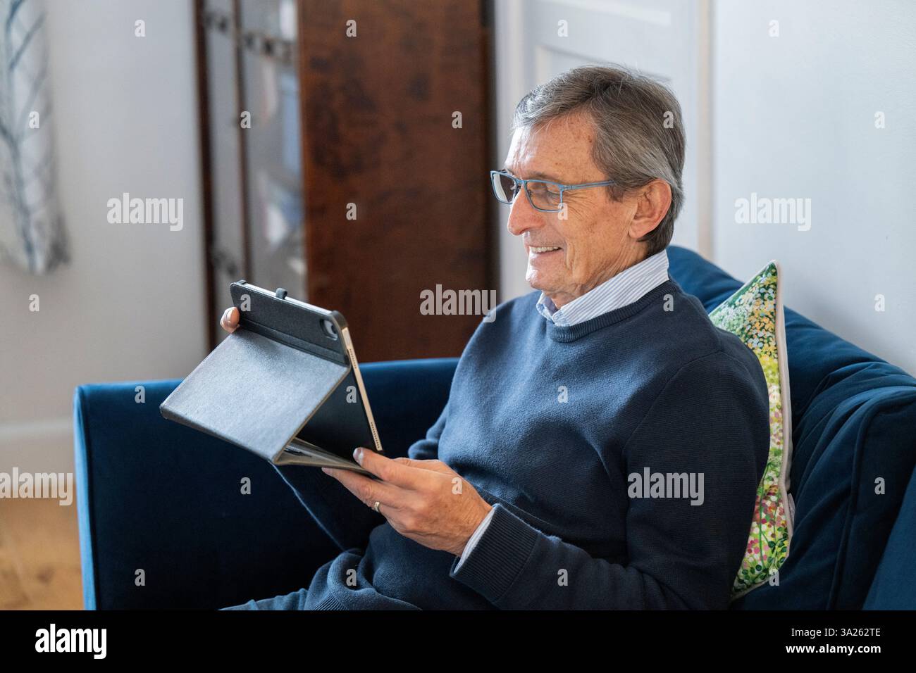 Man sitting on sofa using tablet. Stock Photo