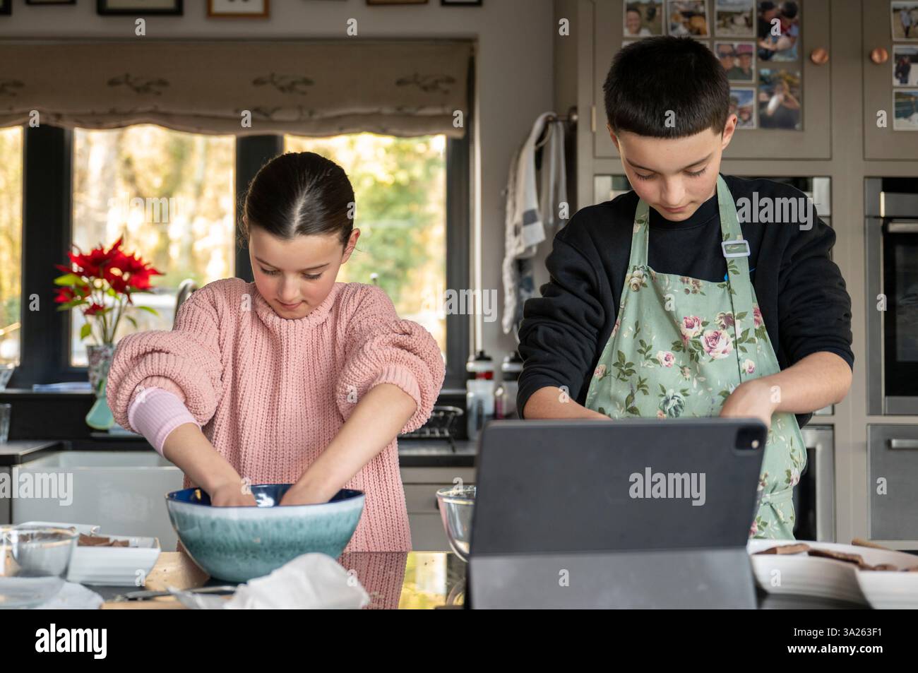 Boy and girl baking together in kitchen using tablet. Stock Photo